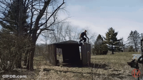 A Man Riding A Bike On Top Of A Wooden Structure In A Field GIF