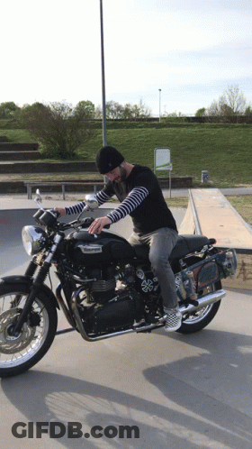 A Man Riding A Black Triumph Motorcycle In A Skatepark GIF