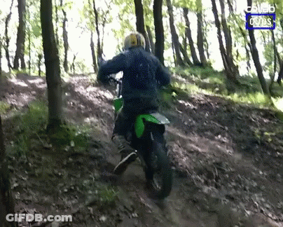 A Man Riding A Dirt Bike In The Woods With A Blue Sign That Says Combo Rides GIF
