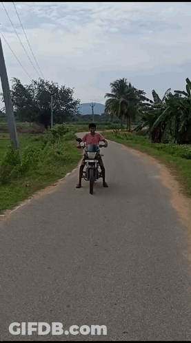 A Man Riding A Motorcycle Down A Dirt Road GIF