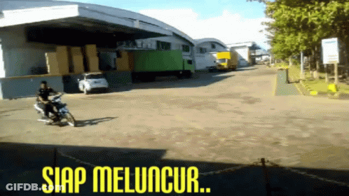 A Man Riding A Motorcycle In Front Of A Warehouse With The Words Siap Meluncur Written On The Bottom GIF