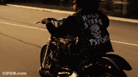 A Man Riding A Motorcycle With A Jacket That Says Psycho On It GIF