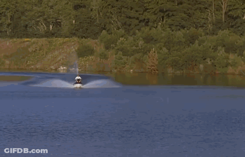 A Man Riding A Purple And Green Jet Ski On A Lake GIF