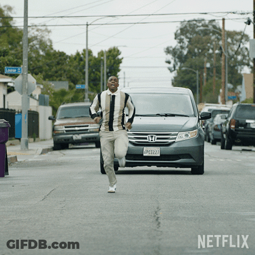 A Man Running Down A Street In Front Of A Netflix Ad GIF