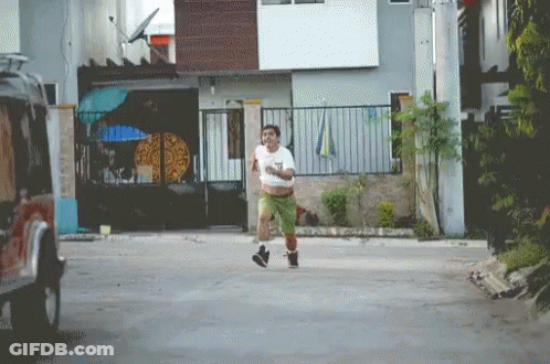 A Man Running Down A Street With A Pizza On The Fence In The Background GIF