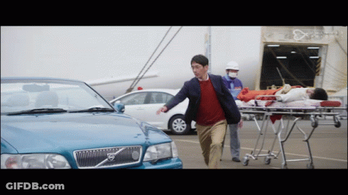 A Man Running Towards A Volvo Car With A Woman On A Stretcher Behind Him GIF
