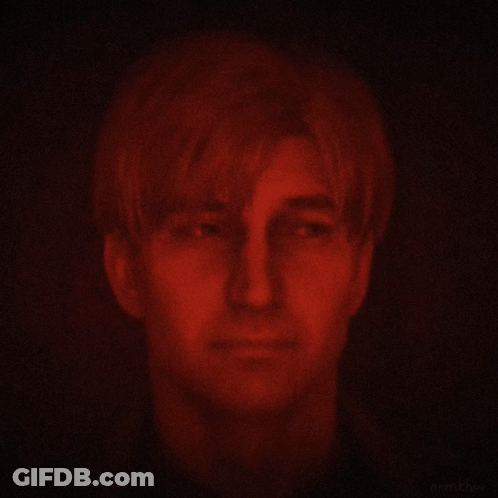 A Man 'S Face Is Glowing Red In The Dark GIF
