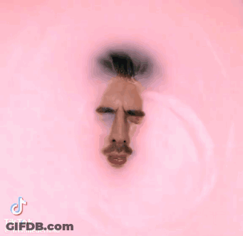 A Man 'S Face Is Visible Through A Hole In A Pink Wall GIF