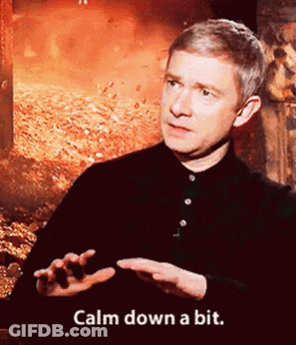 A Man Says Calm Down A Bit In Front Of A Fire Background GIF