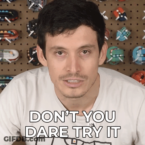 A Man Says " Don T You Dare Try It " In Front Of A Wall Of Toy Cars GIF