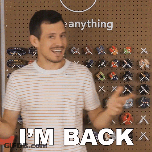 A Man Says I 'M Back In Front Of A Wall Of Toys GIF