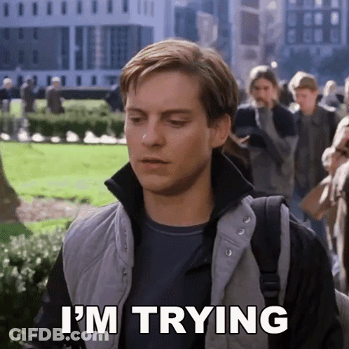 A Man Says I 'M Trying While Walking In A Park GIF