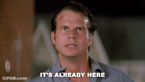 A Man Says " It 'S Already Here " In Front Of A Dark Background GIF