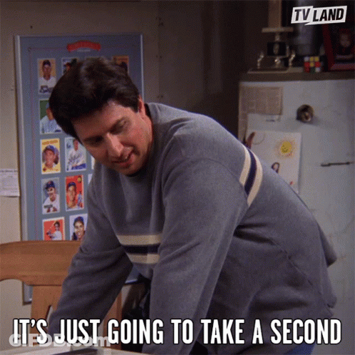 A Man Says It 'S Just Going To Take A Second In Front Of A Tv Land Poster GIF