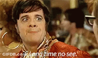 A Man Says Long Time No See While Looking At Another Man . GIF