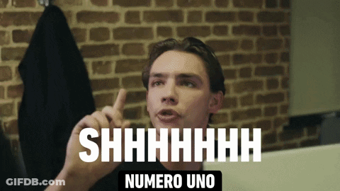 A Man Says Shhhh Numero Uno In Front Of A Brick Background GIF
