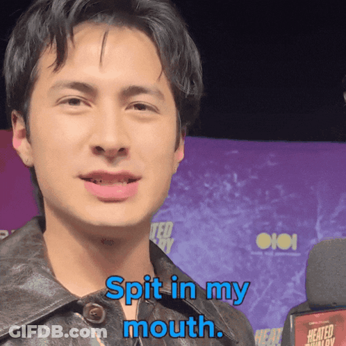 A Man Says " Spit In My Mouth " While Standing In Front Of A Microphone GIF