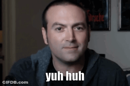 A Man Says Yuh Huh In Front Of A Wall With Pictures On It GIF