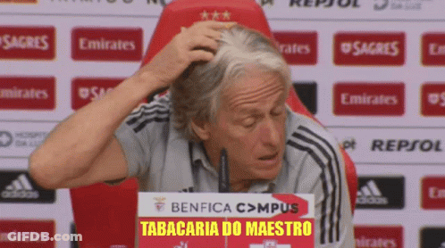A Man Scratches His Head In Front Of A Sign That Says Benfica Campus Tabacaria Do Maestro GIF