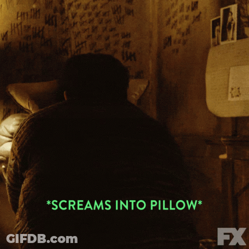 A Man Screams Into A Pillow In A Dark Room GIF