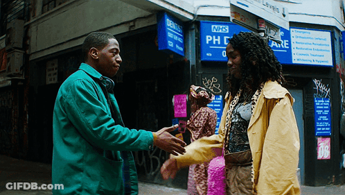 A Man Shakes Hands With Another Man In Front Of A Nhs Sign GIF