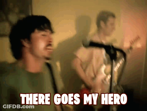 A Man Singing In Front Of A Microphone With The Words " There Goes My Hero " Below Him GIF