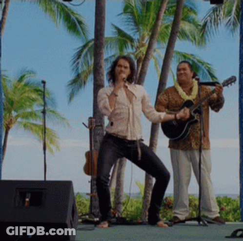 A Man Singing Into A Microphone And Another Man Playing A Guitar GIF