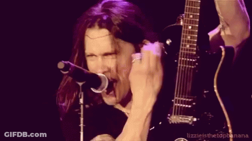 A Man Singing Into A Microphone And Holding A Guitar GIF