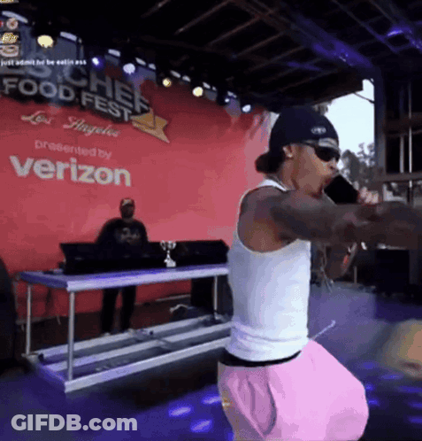 A Man Singing Into A Microphone At A Food Fest GIF