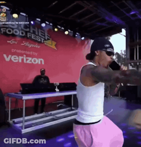 A Man Singing Into A Microphone At A Food Fest GIF