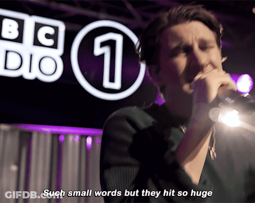 A Man Singing Into A Microphone In Front Of A Bbc Logo GIF