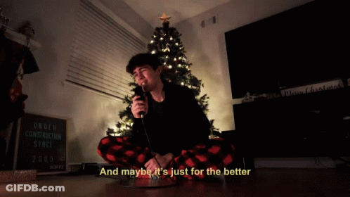 A Man Singing Into A Microphone In Front Of A Christmas Tree With The Words And Maybe It 'S Just For The Better GIF