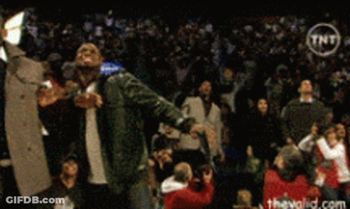A Man Singing Into A Microphone In Front Of A Crowd With A Tnt Logo In The Corner GIF