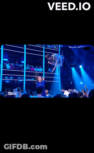 A Man Singing Into A Microphone In Front Of A Crowd With The Words " Veed.io " At The Top GIF