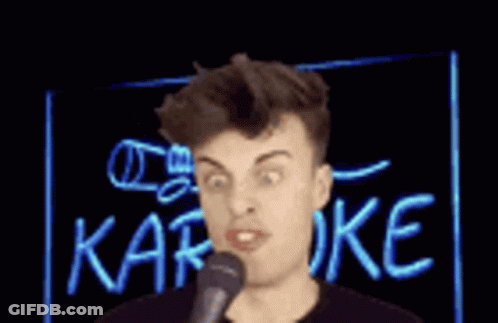 A Man Singing Into A Microphone In Front Of A Neon Sign That Says Karaoke . GIF
