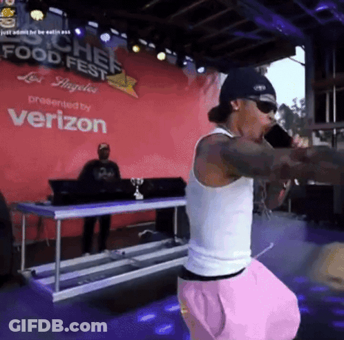 A Man Singing Into A Microphone In Front Of A Sign That Says Chef Food Fest GIF