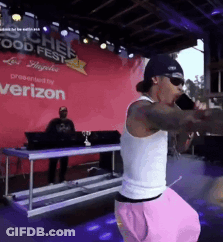 A Man Singing Into A Microphone In Front Of A Sign That Says Chef Food Fest GIF