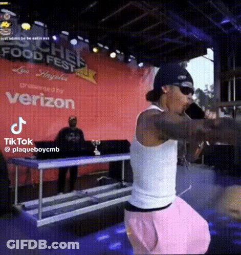 A Man Singing Into A Microphone In Front Of A Sign That Says Food Fest GIF