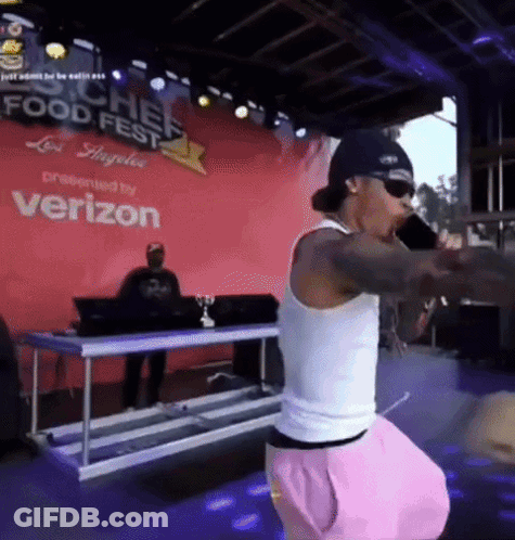 A Man Singing Into A Microphone In Front Of A Verizon Banner GIF