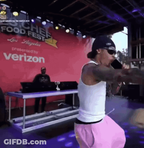 A Man Singing Into A Microphone In Front Of A Verizon Sign GIF