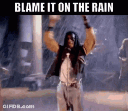 A Man Singing Into A Microphone In The Rain With The Words Blame It On The Rain Below Him . GIF
