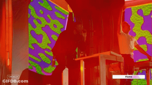A Man Singing Into A Microphone Next To A Man Playing A Keyboard And A Sign That Says Flume GIF