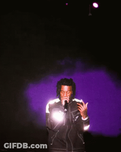 A Man Singing Into A Microphone Wearing A Jacket That Says ' Dg ' On It GIF