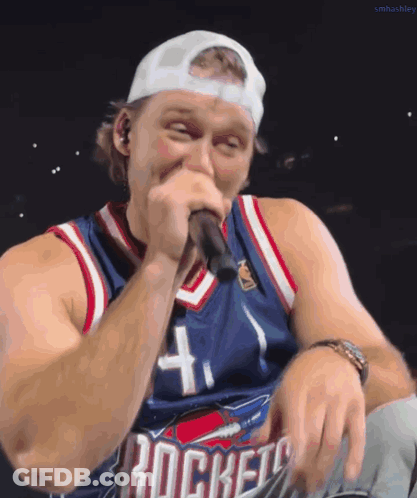 A Man Singing Into A Microphone Wearing A Rockets Jersey GIF