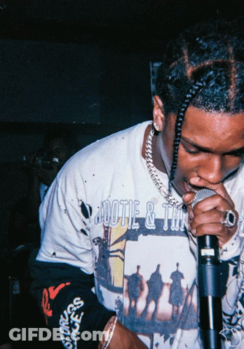 A Man Singing Into A Microphone Wearing A Shirt That Says ' Aootie & Tan ' GIF