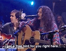 A Man Singing Into A Microphone While Another Man Plays A Guitar GIF