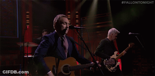 A Man Singing Into A Microphone While Another Man Plays A Guitar On A Stage With The Hashtag #Fallontonight GIF