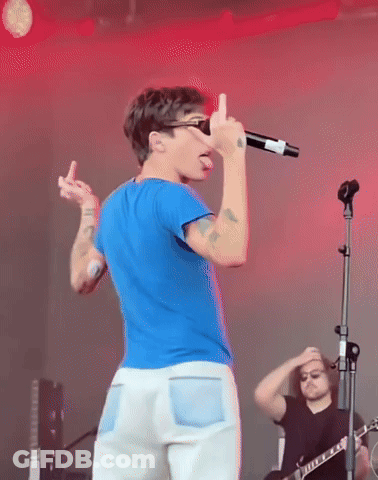 A Man Singing Into A Microphone While Giving The Middle Finger GIF