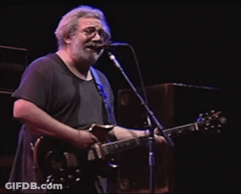 A Man Singing Into A Microphone While Holding A Guitar GIF