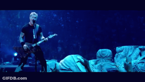 A Man Singing Into A Microphone While Playing A Guitar In Front Of A Crowd GIF